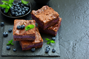 Chocolate brownies with blueberries and cream filling. Dark background.