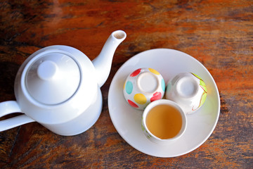 the White ceramic teapot before brewing the hot tea in to white cup with morning sunlight
