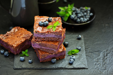 Chocolate brownies with blueberries and cream filling. Dark background.