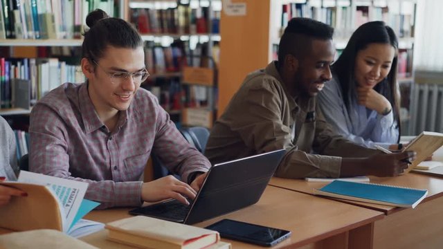 Pan shot of Multi ethnic group of concentrated students preparing for examination while sitting at table at university library