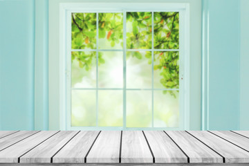Empty wood table with blur window on green bokeh background.
