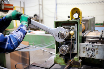 Worker adjusting machinery with large wrench
