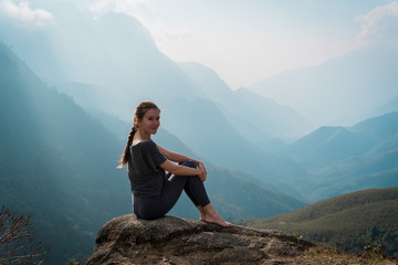 Woman sits on mountain cliff