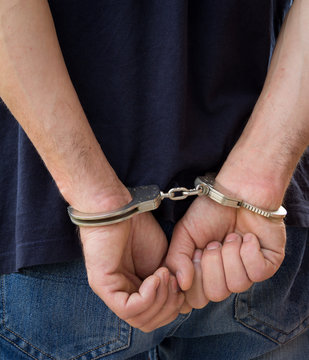 Adult male arrested and handcuffed.Hands with handcuffs from back