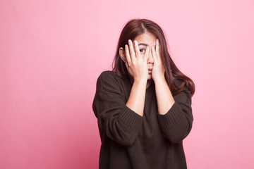 Beautiful young Asian woman peeking through fingers.