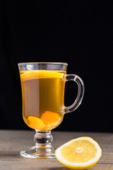 A cup of ginger tea with lemon on a wooden background.