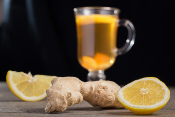 A cup of ginger tea with lemon on a wooden background.