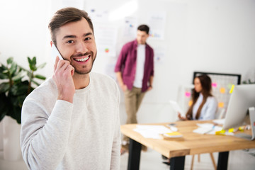 selective focus of smiling businessman talking on smartphone in office