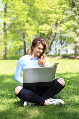 young pretty girl working on laptop outdoor, lying on grass, caucasian 20 years old