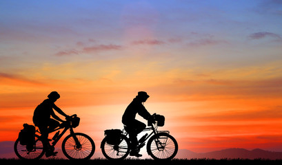 Silhouette man and bike relaxing on blurry sunrise background