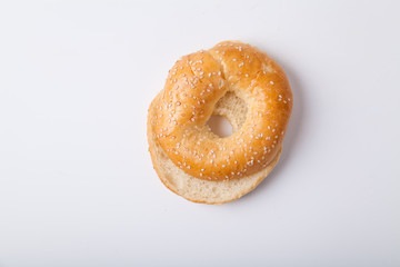 Fresh baked bagle bun with sesame seeds on white background pre-cut for making sandwiches