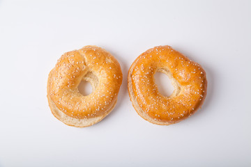 Two fresh baked bagle buns with sesame seeds on white background pre-cut for making sandwiches