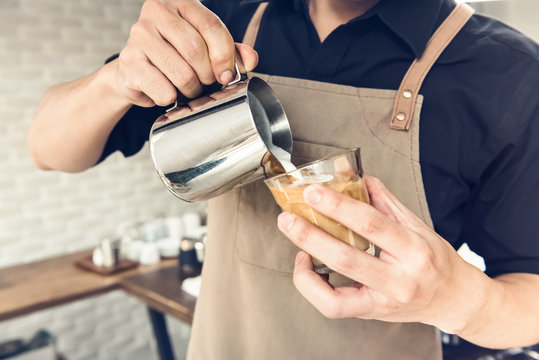 Barista pouring steamed milk into coffee cup making latte art