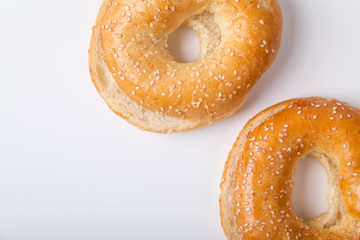 Two fresh baked bagle buns with sesame seeds on white background pre-cut for making sandwiches