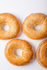 Four fresh baked bagle buns with sesame seeds on white background pre-cut for making sandwiches