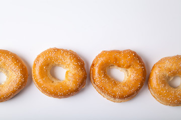 Four fresh baked bagle buns with sesame seeds on white background pre-cut for making sandwiches