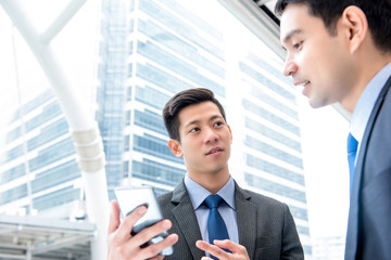 Businessmen discussing information on smartphone outdoors