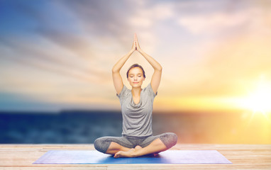 woman meditating in lotus pose on mat outdoors