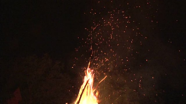 night fire sparks flying in the dark night sky, big night bonfire in a clearing in the forest