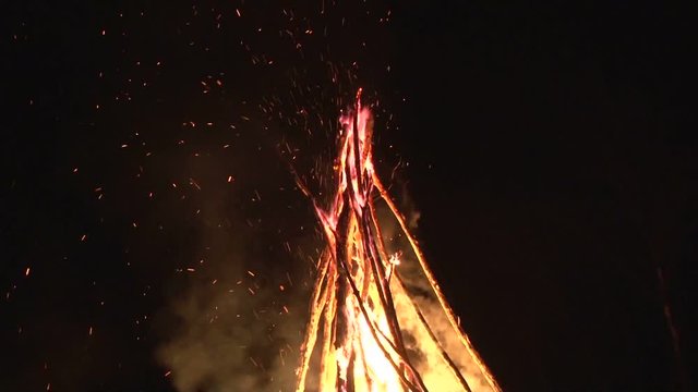 night fire sparks flying in the dark night sky, big night bonfire in a clearing in the forest