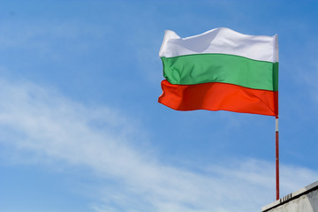 Fototapeta na wymiar Bulgarian flag waving against vibrant blue sky.