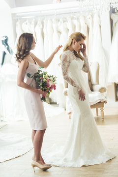 Upset Bride With Friend Holding Flowers In Wedding Salon