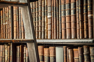 Old vintage encyclopedia books on wooden bookshelf and ladder in a library