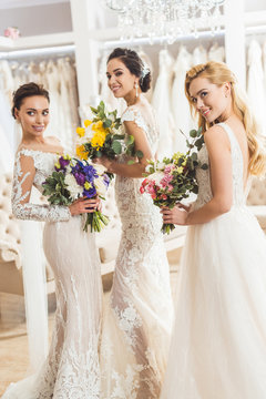 Attractive brides holding bouquets in wedding atelier