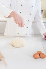 Men hands sprinkle a dough with flour close up. Man preparing bread dough