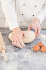 Men hands sprinkle a dough with flour close up. Man preparing bread dough