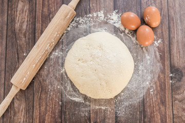 Men hands sprinkle a dough with flour close up. Man preparing bread dough