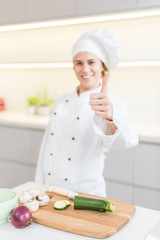 Beautiful young woman chef cooking in modern kitchen