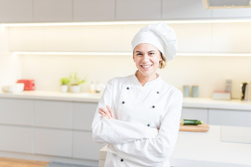 Beautiful young woman chef cooking in modern kitchen