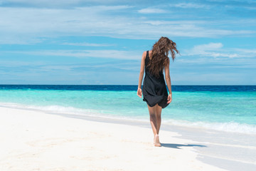 Fototapeta na wymiar Woman walking on beach with pure water of ocean in Maldives