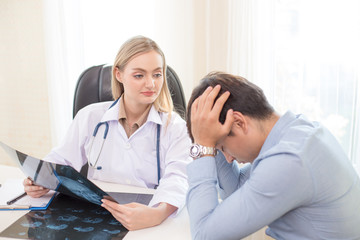 Obraz premium Attractive female doctor showing x-ray films to patient at clinic. Medical and Health care concept.