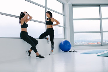 Obraz premium Two girls taking break after working out in gym