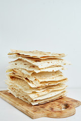 plain grilled pita bread on a wooden cutting board with a white background.