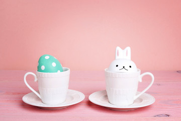 Easter cups with egg and bunnny on a pink table.
