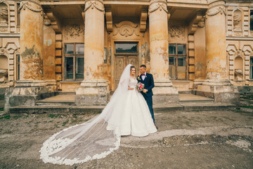 Beautiful romantic wedding couple of newlyweds hugging and kiss each other near old castle with columns and ancient door