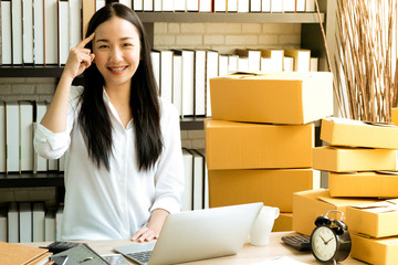 asian businesswoman sitting happy to thinking my work with laptop and box package, warm tone process style