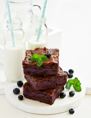 Chocolate brownies with blueberries and cream filling. Dark background.
