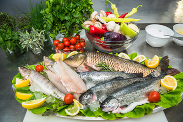 Fresh fish on ice with vegetables and spices. Healthy food preparation
