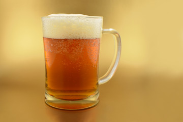 Beer glass with handle stock images. Glass with beer on a golden background. Beer on a golden background with copy space for text. Festive golden background