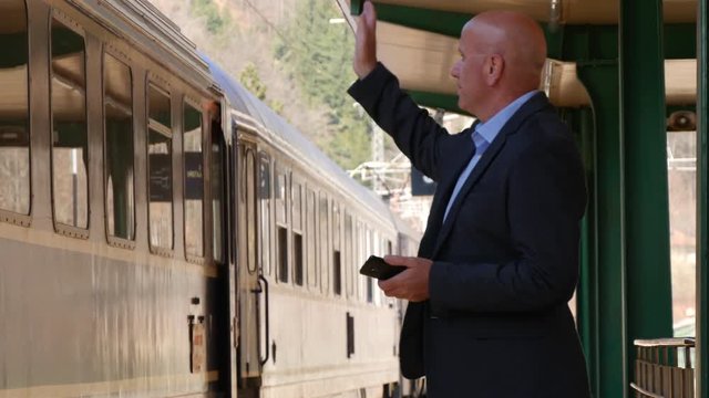 Businessman Gesturing Goodbye Hand Sign Train Start Moving from Railway Station