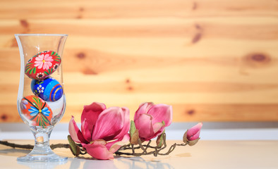 Bunte Ostereier im Glas vor einer Holzwand Holz Magnolie
