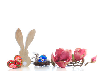 Holzhase Osterhase mit bunten Ostereiern und Blumenzweigen auf weissem Hintergrund