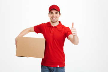 Cheerful young delivery man showing thumbs up.