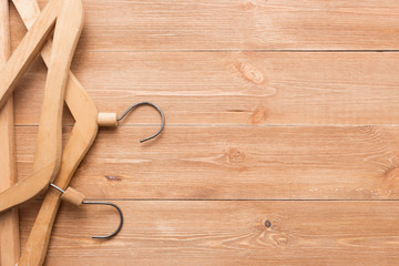 Wooden hanger for clothes on wooden background top view flat lay