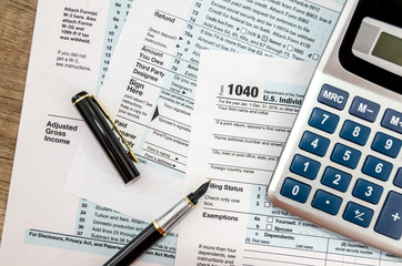 Calculator and pen with 1040 tax form