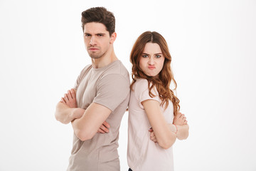 Offended guy and girl wearing beige t-shirts resenting and acting like arguing couple standing back to back with arms crossed, over white background